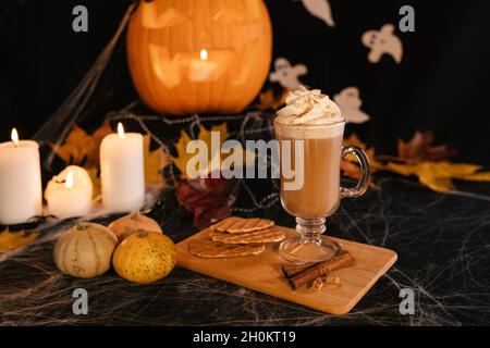 Halloween Latte. Würziger Latte Kaffee in Halloween Dekorationen. Kürbis, Latte, Halloween, Kommerzielle Inhalte. Kaffeetasse auf dem Halloween-Tisch Stockfoto