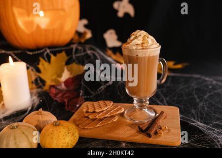 Halloween Latte. Würziger Latte Kaffee in Halloween Dekorationen. Kürbis, Latte, Halloween, Kommerzielle Inhalte. Kaffeetasse auf dem Halloween-Tisch Stockfoto