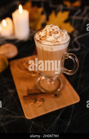 Halloween Latte. Würziger Latte Kaffee in Halloween Dekorationen. Kürbis, Latte, Halloween, Kommerzielle Inhalte. Kaffeetasse auf dem Halloween-Tisch Stockfoto
