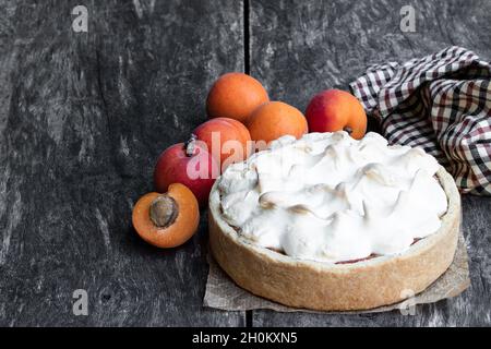 Leckere Meringuekuchen mit frischer Aprikose auf Holztisch Stockfoto