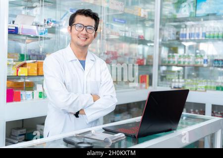 Glücklicher Apotheker, der in einer Apotheke oder Apotheke arbeitet. Apotheker mit dem Laptop in der Apotheke. Stockfoto