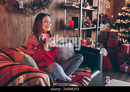 Foto von ziemlich verträumt junge Frau gekleidet roten Pullover machen Neujahr Wünsche lächelnd drinnen Zimmer Haus Stockfoto