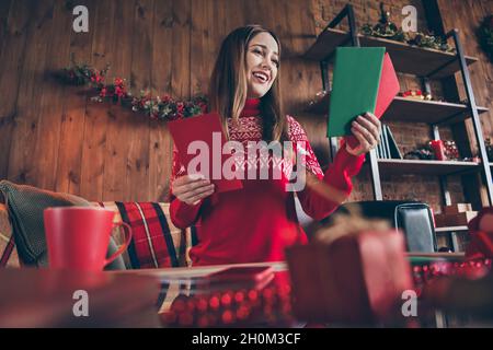 Foto von charmanten süßen jungen Frau gekleidet roten Pullover immer Neujahr Glückwünsche lächelnd drinnen Zimmer Haus Stockfoto