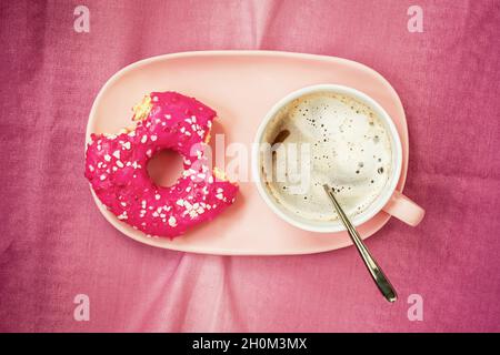 Leuchtend rosa gebitzte Krapfen in Teller und Kaffee, Draufsicht. Lebensmittelkonzept Stockfoto