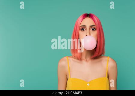 Junge Frau mit rosa gefärbten Haaren Blasen Kaugummi auf blau isoliert Stockfoto