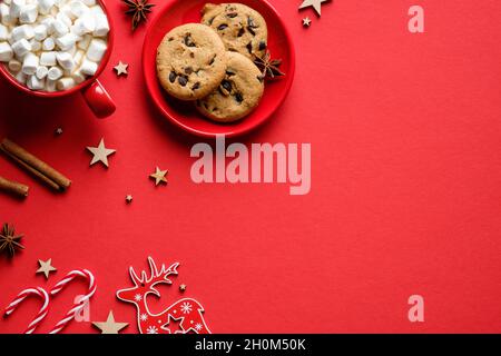 Flache Lay-Komposition mit weihnachtlichen Gebäck-Cookies, heißer Schokolade mit Marschmalchen, Zimtstangen, Zuckerstangen auf rotem Hintergrund. Frohe Weihnachten h Stockfoto