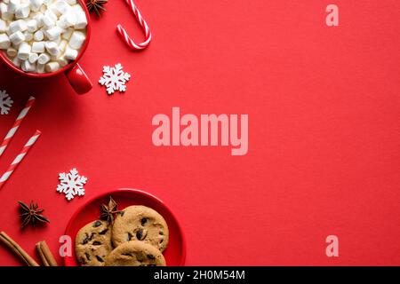 Weihnachtskarten-Design. Flach legen Tasse heiße Schokolade mit Marshallows, Süßigkeiten Stöcke, Haferflocken Cookies auf rotem Hintergrund. Stockfoto