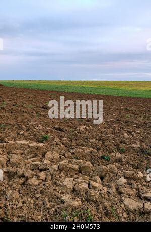 Abstrakte Landschaft aufgenommen mit einem frisch gepflügten landwirtschaftlichen Feld gegen den bewölkten Himmel im Herbst. Gesehen in Deutschland im Oktober. Stockfoto