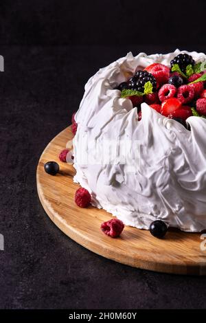 Köstlicher Pavlova-Kuchen mit Baiser und frischen Beeren auf Schwarz Stockfoto
