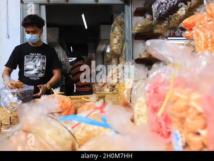 Bandung, Indonesien-September 29,2021: Snack-Händler stecken gebratenen Tempeh in eine Plastiktüte Stockfoto