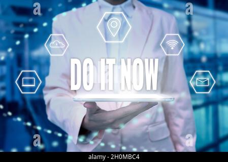 Textunterschrift mit „Jetzt machen“. Business-Ansatz nicht zögern und beginnen Sie sofort zu arbeiten oder Dinge zu tun Lady Uniform stehend Tablet Hand Stockfoto