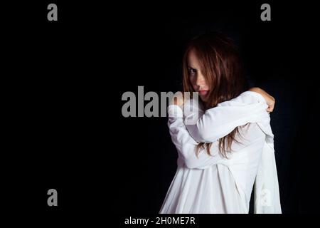 Konzept der psychischen Probleme und der psychischen Gesundheit. Porträt einer Frau in einer weißen Zwangsjacke mit einem verrückten traurigen Look Stockfoto