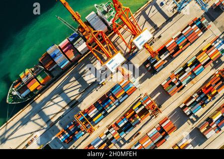 Container in internationalen Schiffsanlegestelle warten auf Import oder Export und Transport. Draufsicht auf das Verladen von Containern auf dem Schiff im Hafen Stockfoto