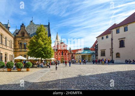 Das Innere und der Innenhof des Schlosskomplexes mit einem Café im Freien, Touristen und der St.-Georgs-Basilika in Prag, Tschechien. Stockfoto