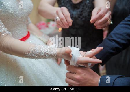 Die Braut legt ihr das Taschentuch in die Hände. Die Hand der Braut ist am Bogen befestigt Stockfoto