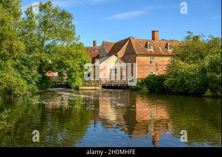 Die roten Backsteingebäude von Flatford Mill, die von der anderen Seite des Flusses Stour in „Constable Country“, Suffolk, England, gesehen wurden. Stockfoto