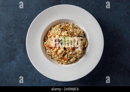 Risotto, italienischer Reis mit Pilzen, Gemüse und Petersilie auf weißem Porzellanteller serviert Stockfoto