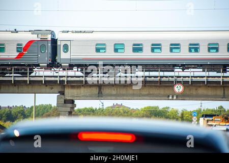 Der Schnellzug fährt im Sommer über die Autobahn, auf der die Autos fahren Stockfoto