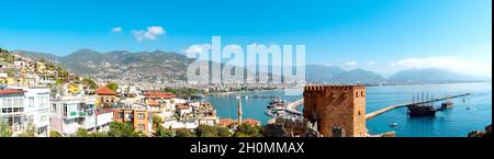 Panorama der Stadt Alanya von einem der Gipfel der Burg mit Blick auf die türkischen Häuser, den Kizil Kule Turm und den Hafen. Stockfoto