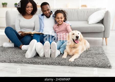 Junge schwarze Familie Lesebuch mit Hund zu Hause Stockfoto