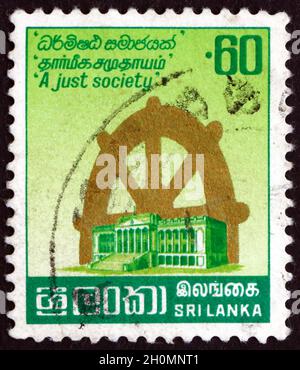 SRI LANKA - UM 1983: Eine in Sri Lanka gedruckte Marke zeigt Parlament und Lebensrad, um 1983 Stockfoto