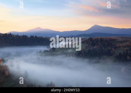 Herbstlandschaft. Landschaft mit den Bergen, Sonnenaufgang, blauer Himmel mit orangefarbenen Wolken. Landschaft, Felder, Wälder im Morgennebel. Touristenr Stockfoto