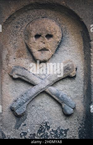 Schädel und Kreuzknochen auf dem Grab im St. Lawrence Kirchhof des Pestdorfes Eyam, Peak District, Derbyshire, England Stockfoto