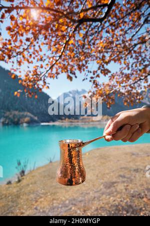 Kupfer Cezve für Kaffee im Herbst See Camping in den Bergen. Zubereitung von Kaffee im Freien Konzept Stockfoto