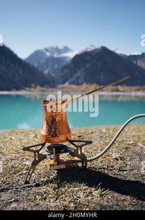Kupfer Cezve für Kaffee im Herbst See Camping in den Bergen. Zubereitung von Kaffee im Freien Konzept Stockfoto