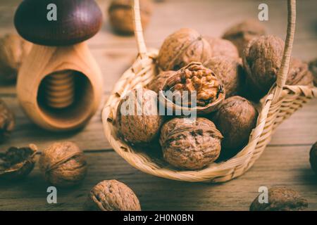 Bio-Walnüsse mit kleinem Nussknacker als Backzutaten auf Holzboden Stockfoto