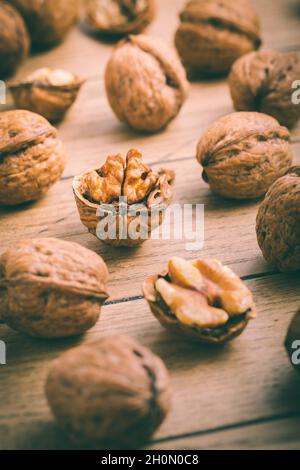 Bio-Walnüsse mit kleinem Nussknacker als Backzutaten auf Holzboden Stockfoto