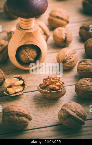 Bio-Walnüsse mit kleinem Nussknacker als Backzutaten auf Holzboden Stockfoto