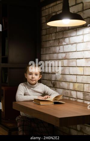 Ein kleines Schulmädchen liest im Loft ein Buch. Hochwertige Fotos Stockfoto