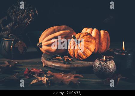 Stillleben für Thanksgiving mit Kürbissen und Herbstblättern auf Holzgrund Stockfoto