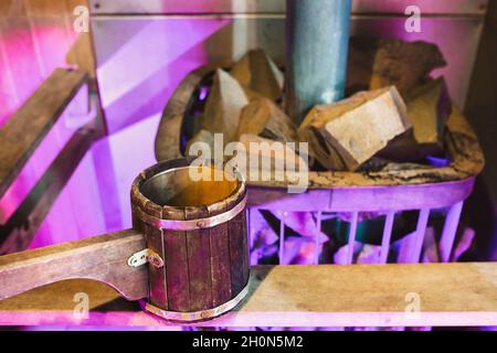 Holzpfanne im Badehaus in der Nähe des Ofens - heiße Steine gießen, um Wasser zu dampfen Stockfoto