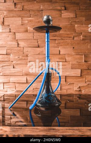 Shisha auf einem Glastisch auf dem Hintergrund einer hölzernen Wand - ein gemütlicher Ort Stockfoto