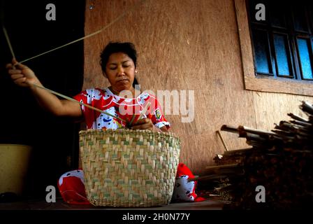 Eine Frau aus der ethnischen Añu-Indianergemeinde, die im Dorf Sinamacia an der Lagune von Sinamcia Kunsthandwerk anstellt. Die Lagune von Sinamaica ist eine große Wasserausdehnung nordwestlich des Zulia-Staates, Venezuela. Das Dorf Sinamacia, das von den ethnischen Añu-Indianern bewohnt wird, ist eines der letzten schwimmenden Dörfer der Erde. Sie leben in der Gegend in Häusern über Wasser, die als Palafitos bekannt sind, seit der vorkolonialen Zeit. Sie nutzen den Wasserkörper zum Angeln, für den Transport und andere Aktivitäten. Für den Transport werden Holzkanus oder kleine Motorboote verwendet. Das Leben in der Lagune ist derzeit von SoC bedroht Stockfoto