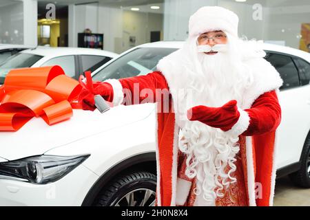 Santa claus, die schlüssel eines autos auf gelbem hintergrund hält