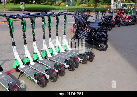 Dutzende von Leihfahrrädern und E-Bikes stehen auf einem Bürgersteig in Seattle und bieten Lime-Roller, Wheels Leihfahrräder und Spin E-Roller an. Stockfoto