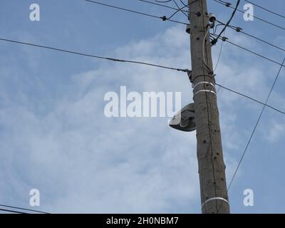 Eine alte hölzerne elektrische Stange mit einer Lampe und Stromkabeln, die darauf hängen. Nahaufnahme. Stockfoto