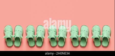 Katzengesicht-Slipper in einer Reihe über orangefarbenem Hintergrund mit Copy-Pace. Muster von Celadon grünen gemütlichen Hausschuhen auf korallenfarbenen Oberfläche. Speicherplatz kopieren. Stockfoto