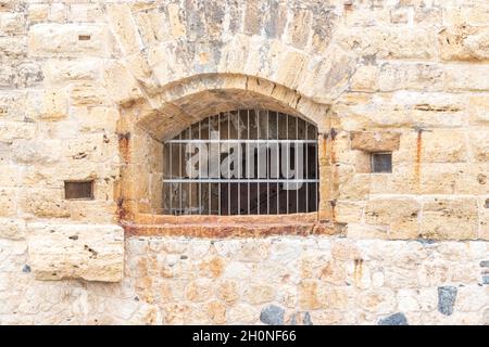 Fenster mit Eisengitter an der Steinwand. Stockfoto