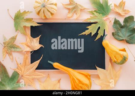 Tafel und gelbe Kürbisse, Herbstblätter. Modell. Halloween-Konzept. Draufsicht, flach liegend Stockfoto