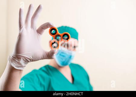 Ein Arzt in einer Maske und Handschuhen, mit einem Spinner in den Händen. Stockfoto