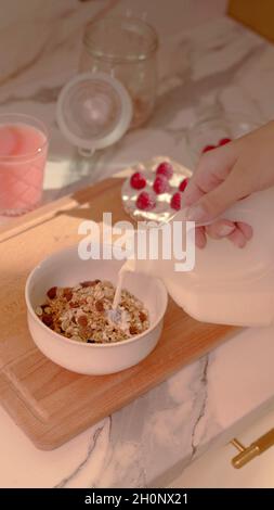 Eine Frau bereitet eine Schüssel Müsli zu Stockfoto