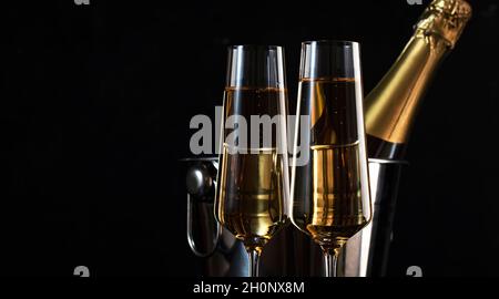 Zwei Sektgläser und eine Flasche im Eimer auf schwarzem Hintergrund. Happy New Year oder Merry Christmas Komposition Stockfoto