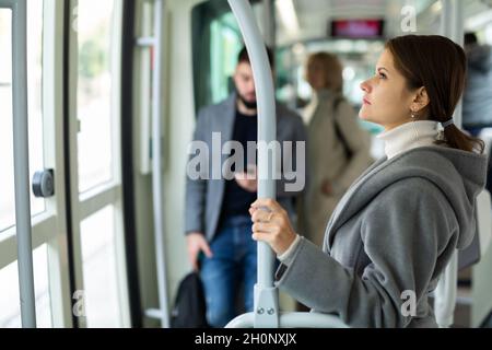 Junge, nachdenkliche Frau in der Straßenbahn Stockfoto