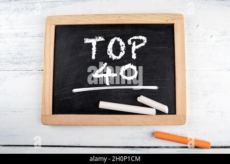 Top 40. Schwarzes Kreidetafel mit Kreidestücken auf einem weißen Tisch. Stockfoto