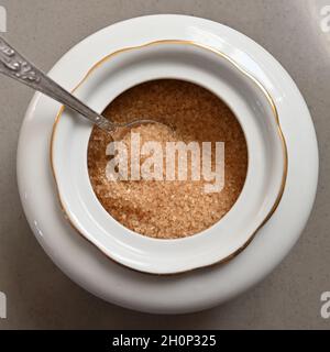 Rohrzucker in einer Porzellanzuckerschale mit einem Löffel aus der Nähe Stockfoto