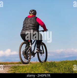 Übergewichtige Frau Schlankheitskur auf dem Fahrrad im Freien im Park. Gesundes Lifestyle-Konzept. Straßenfoto, selektiver Fokus, Reisefoto. Stockfoto